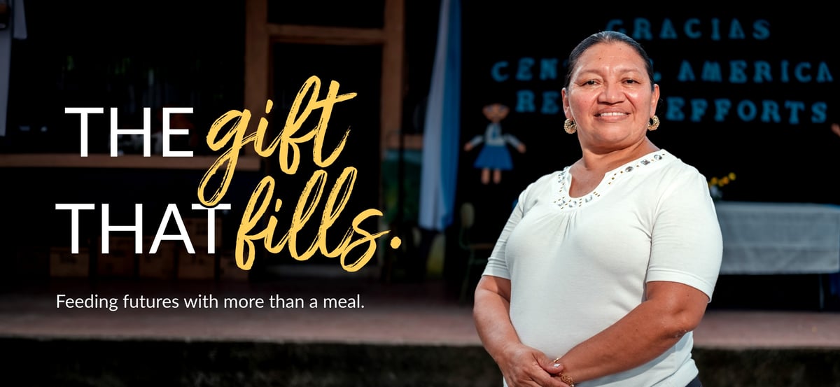 A woman standing confidently at a partner organization with overlaid text "The gift that fills. Feeding futures with more than a meal."