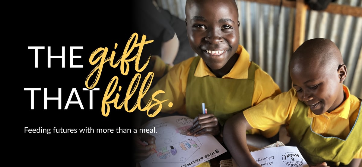 Email header image with "The Gift That Fills" wordmark and the tagline "Feeding futures with more than a meal." The photo is of two students doing schoolwork in their classroom where they receive Rise Against Hunger meals.