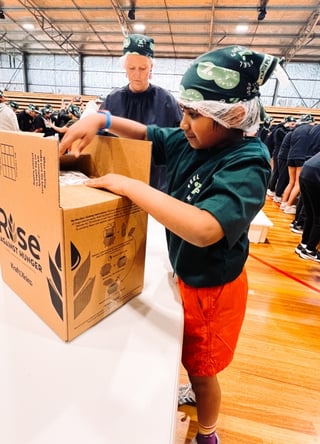 A photo of a child packaging meals for Rise Against Hunger.